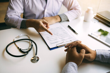 Doctor hand holding pen writing patient history list on note pad and talking to the patient about medication and treatment.