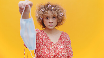 Young girl holding mask and showing it to the camera. Girl with serious facial expressions looking...