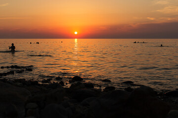 Silhouettes of people swimming in the sea at sunset. Russia, Sea of Azov, Krasnodar Territory, Yeysk.