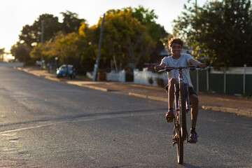 teen boy doing wheelie on bike on quiet street