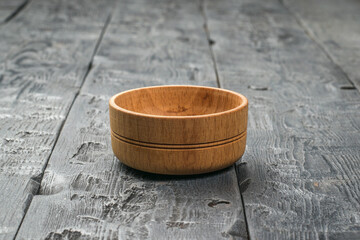 Naklejka premium A small wooden cup on a dark wooden table.