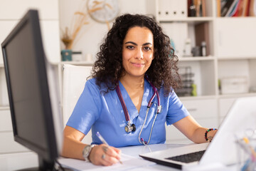 Portrait of female doctor working on laptop computer consulting patient online, telemedicine concept