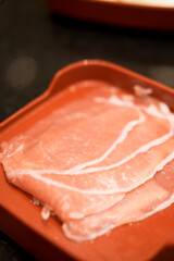 Sliced pork in the red tray.