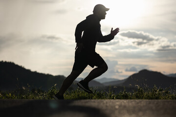 Silhouette Young man wearing sportswear running outdoor nature mountain background. Man jogging on the country side road. Training athlete outdoor concept.