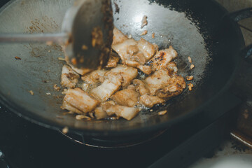 Cooking deep fried pork belly with garlic and pepper in hot pan