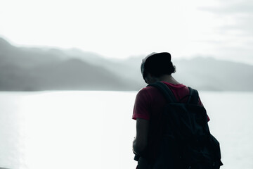 young teen Caucasian boy hipster man adult backpacker enjoying camera on beautiful landscape scenery view jungle mountains forest at Kanchanaburi water river dam National Park, Thailand.