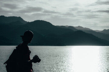 young teen Caucasian boy hipster man adult backpacker enjoying camera on beautiful landscape scenery view jungle mountains forest at Kanchanaburi water river dam National Park, Thailand.