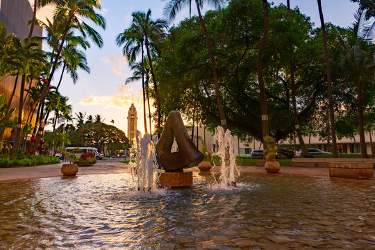 Downtown Honolulu fountains with Aloha Tower in the background at sunset
