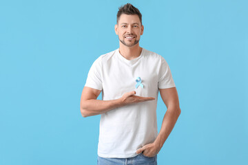 Man with blue ribbon on color background. Prostate cancer awareness concept - obrazy, fototapety, plakaty