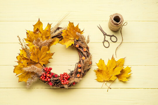 Beautiful autumn wreath with craft supplies on color wooden background