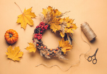 Beautiful autumn wreath with craft supplies on color background