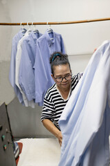 An elderly woman who is a housewife folding clothes at the laundry.