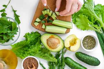 Woman cooking salad of fresh green vegetables and herbs. Raw food concept. Vegan menu. Cooking...