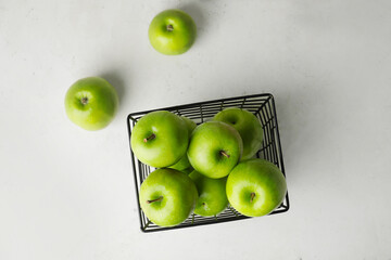 Basket with fresh green apples on light background