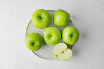 Plate with fresh green apples on white background