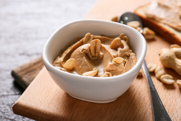 Bowl with tasty peanut butter on table, closeup