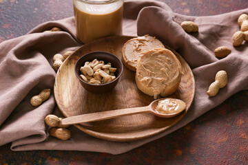 Plate with tasty peanut butter and bread on color background