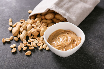 Bowl with tasty peanut butter on dark background