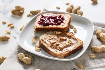 Plate with tasty bread, peanut butter and jam on table