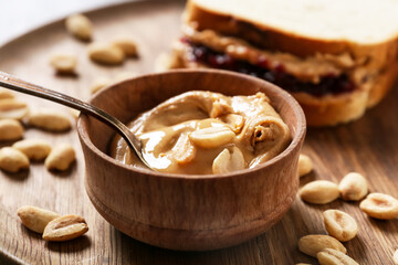 Bowl with tasty peanut butter on tray, closeup