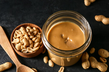 Jar with tasty peanut butter on dark background