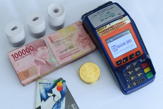 pile of hundred thousand rupiah banknotes, BANK BRI credit cards and bitcoins as well as an EDC (ELECTRONIC DATA CAPTURE BANK BRI) machine, photo taken on June 15, 2021 in city of Lumajang, indonesia