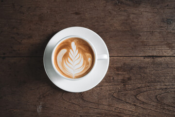 Latte art coffee on wooden table in coffee shop