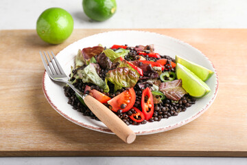 Plate with tasty cooked lentils and vegetables on table