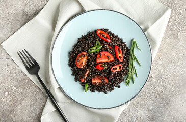 Plate with tasty cooked lentils and vegetables on grunge background