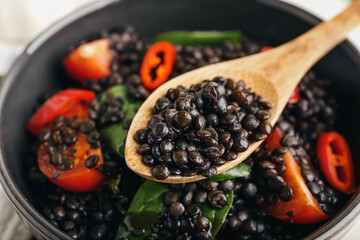 Eating of tasty cooked lentils and vegetables from bowl, closeup