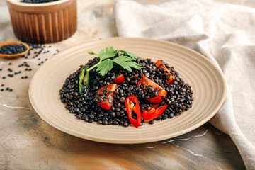 Plate with tasty cooked lentils and vegetables on grunge background