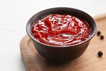 Bowl with tasty barbecue sauce on light background