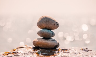 Pyramid stones on the seashore on a sunny day on the blue sea background. Happy holidays. Pebble beach, calm sea, travel destination. Concept of happy vacation on the sea, meditation, spa, calmness.