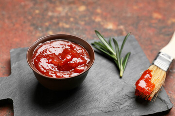 Bowl with tasty barbecue sauce and brush on grunge background
