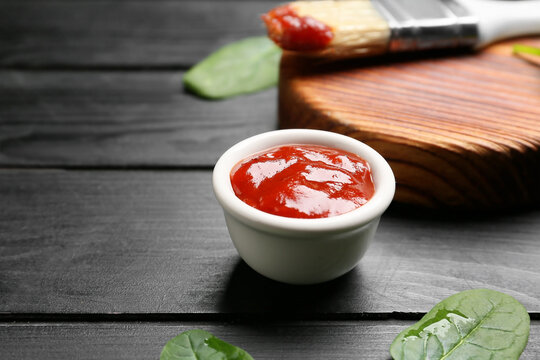 Bowl with tasty barbecue sauce on dark wooden background