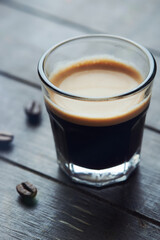Coffee in glass cup on dark wooden background. Close up.
