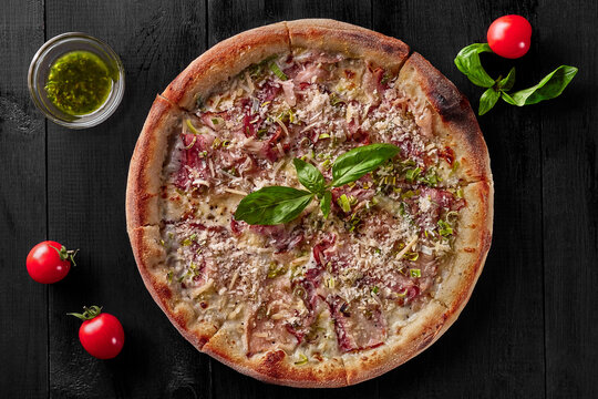 Pizza with cream sauce, mozzarella, bacon, leek and parmesan