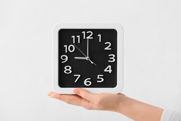 Female hand with stylish clock on light background, closeup