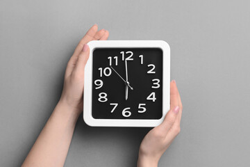 Female hands with stylish clock on grey background, closeup