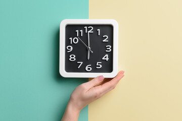 Female hand with stylish clock on color background, closeup