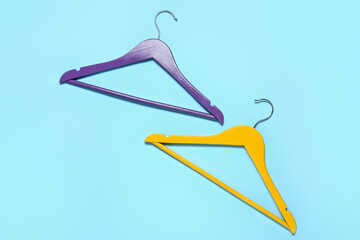 Stylish clothes hangers on color background