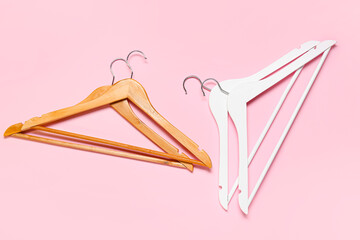 Stylish clothes hangers on color background