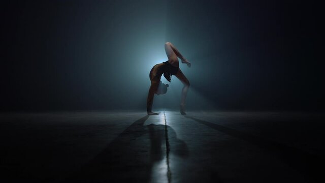 Flexible gymnast doing backbend exercises. Beautiful woman stretching indoors.