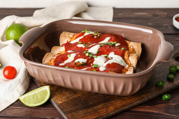 Baking dish with tasty cooked enchilada on table