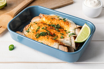Baking dish with tasty cooked enchilada on table