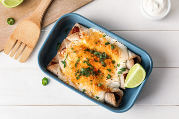 Baking dish with tasty cooked enchilada on table