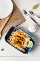 Baking dish with tasty cooked enchilada on table