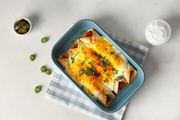 Baking dish with tasty cooked enchilada on white background