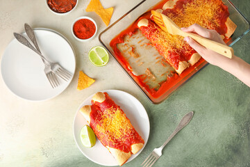 Woman putting hot enchilada from baking dish onto plate