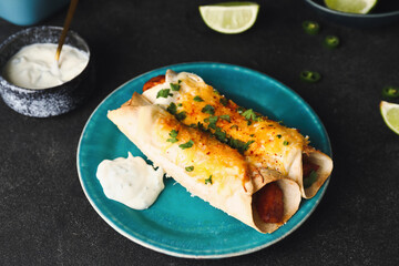 Plate with tasty cooked enchilada on dark background